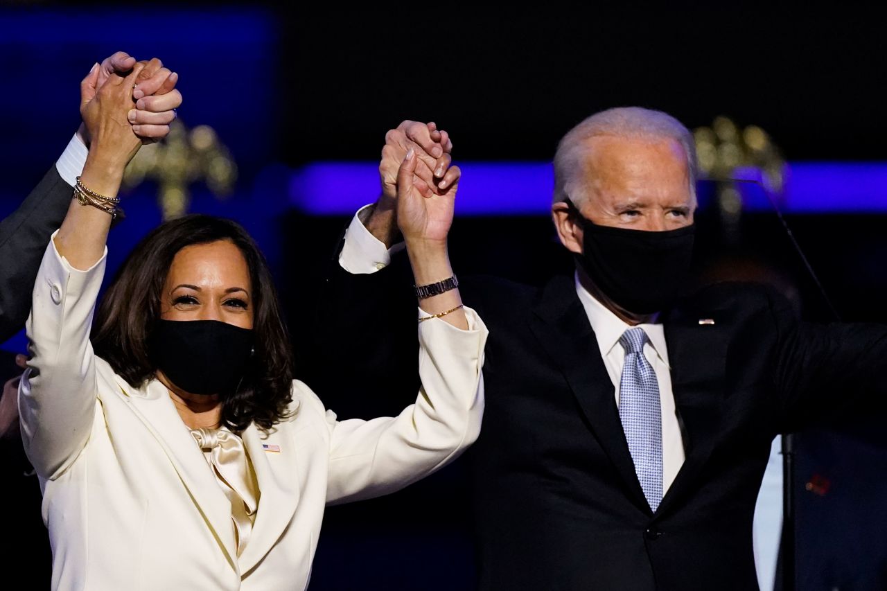 Vice President-elect Kamala Harris holds hands with President-elect Joe Biden and her husband Doug Emhoff as they celebrate Saturday, Nov. 7, 2020, in Wilmington, Del