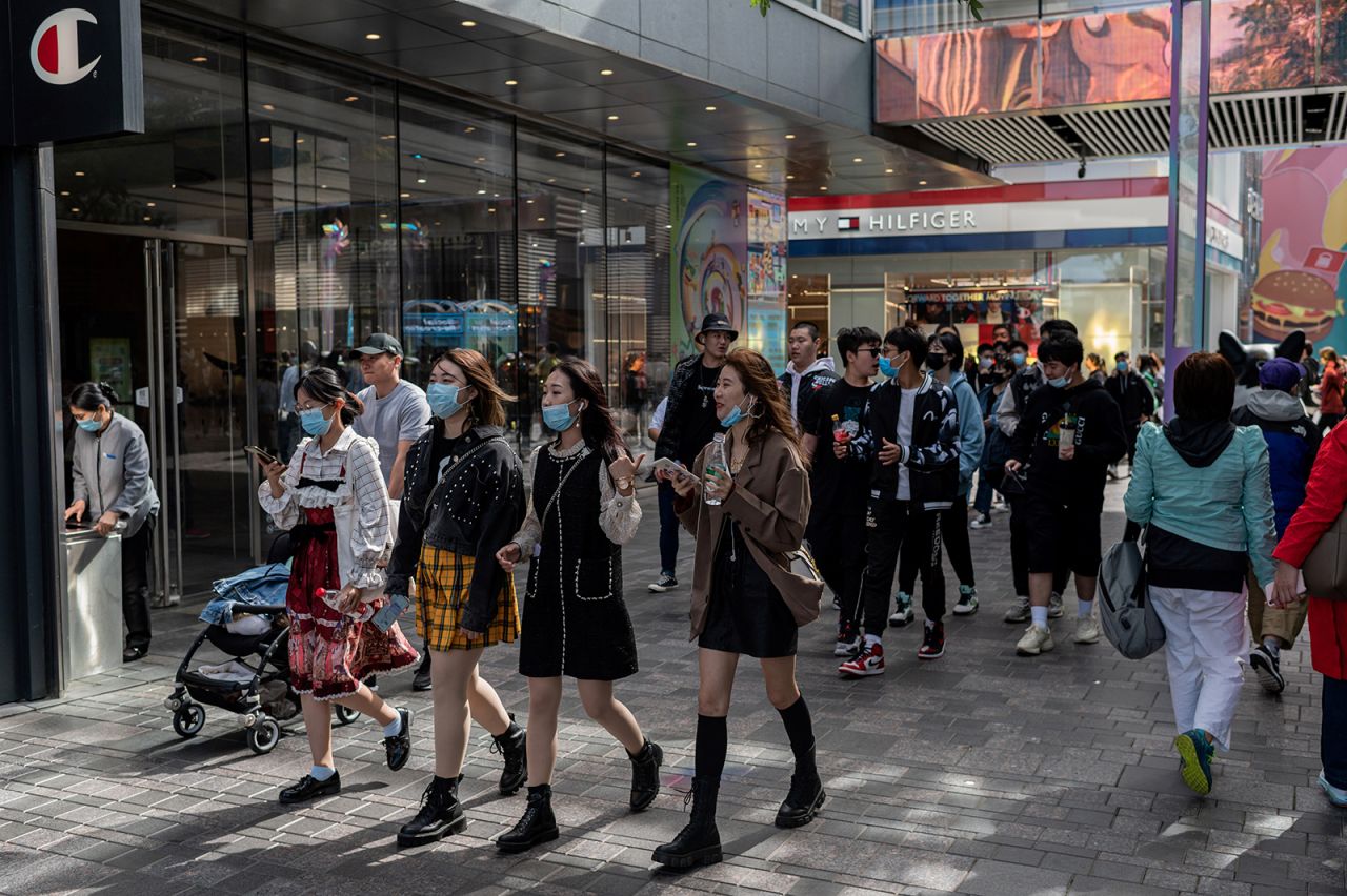 People wearing face masks as a preventive measure against Covid-19 walk outside a shopping mall complex during the country's national "Golden Week" holiday in Beijing, China on October 2.