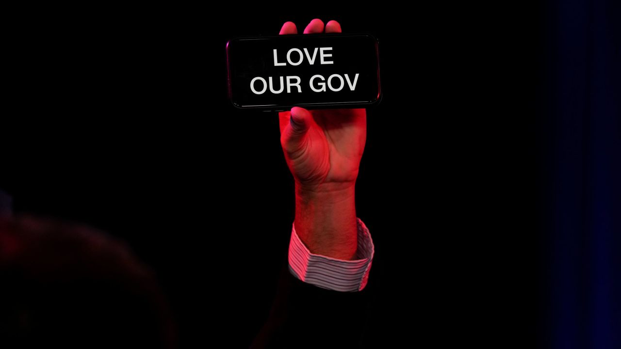 A person holds up a phone that reads "love our gov" before DeSantis' remarks on Tuesday night.