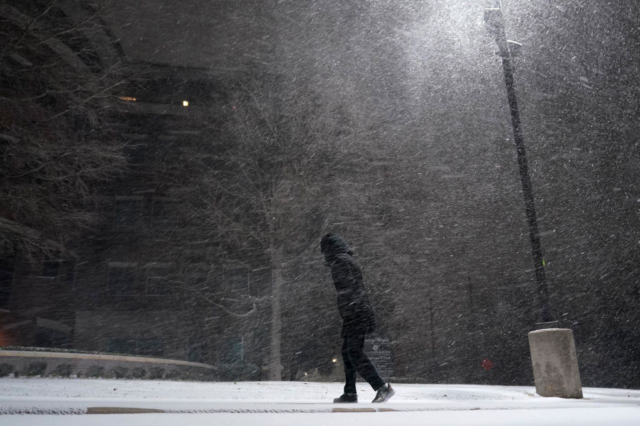 A woman walks through falling snow in San Antonio, Sunday, February 14.