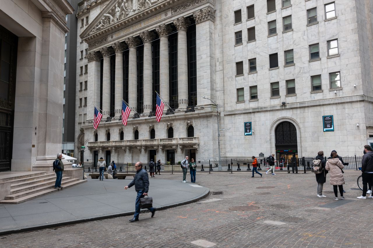 People walk by the New York Stock Exchange on March 20.