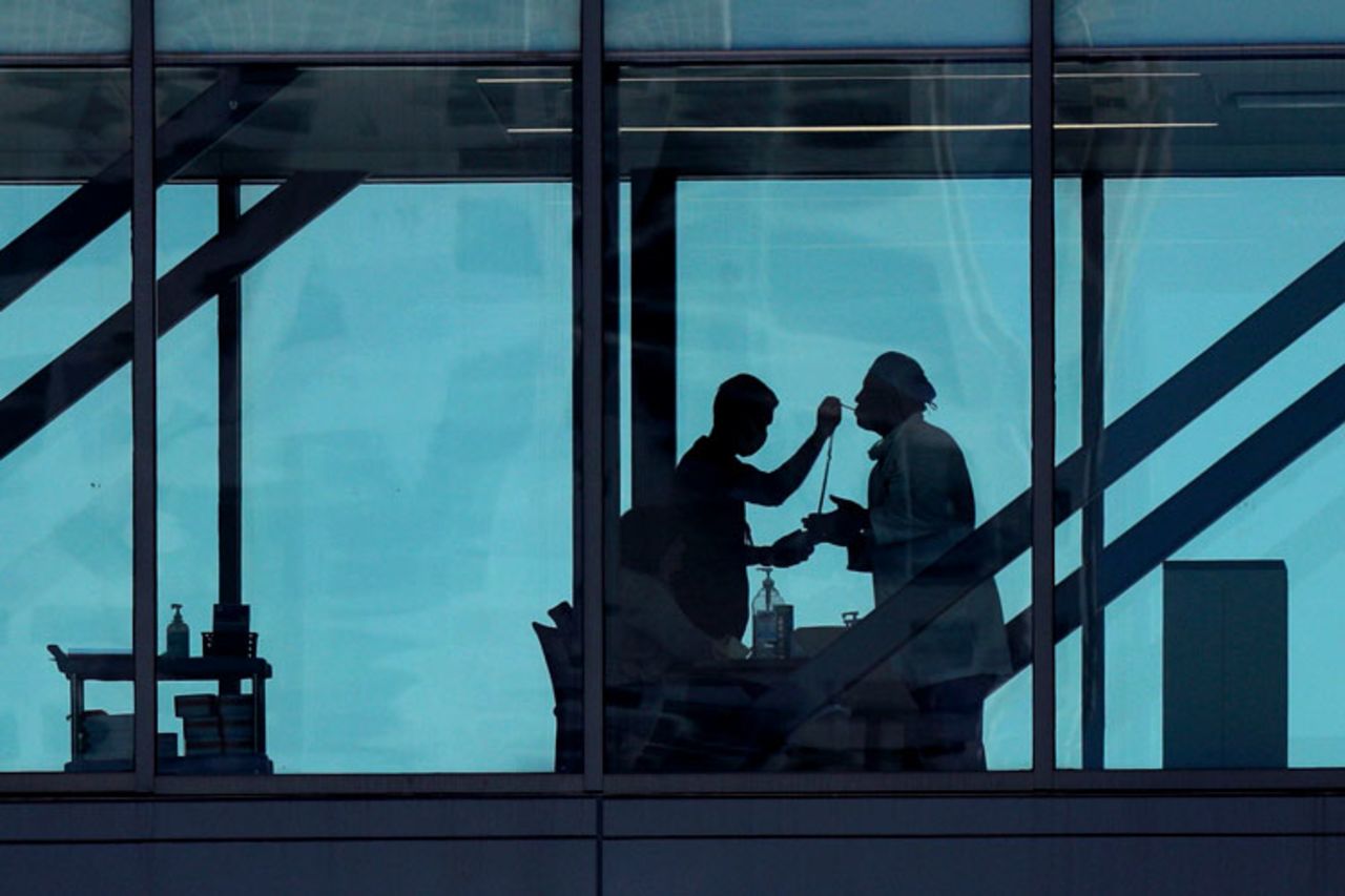 A man has her temperature taken at a control point on a covered footbridge to be screened for symptoms before entering the Dell Deton Medical Center at the University of Texas in Austin, Texas, on Wednesday, March 25.