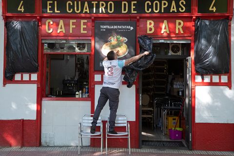 A worker uncovers the front of a bar preparing to reopen in Madrid, Spain, Monday, May 25. 