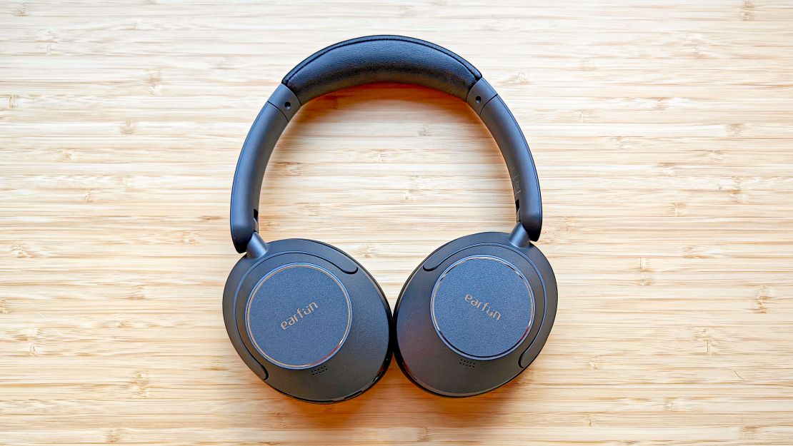 A pair of Earfun Wave Pro headphones on a wooden desk.