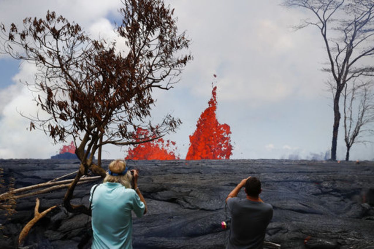 Heath Dalton, right, and Jim Carpenter take pictures as fissures spew lava in the Leilani Estates subdivision near Pahoa, Hawaii, on Tuesday, May 22, 2018. 