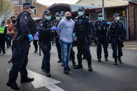 A man is detained by police on Sunday in Melbourne after anti-lockdown protesters organized a "freedom walk" to demonstrate against Covid-19 restrictions. 