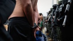 Ecuadorean police stand behind suspected gang members.