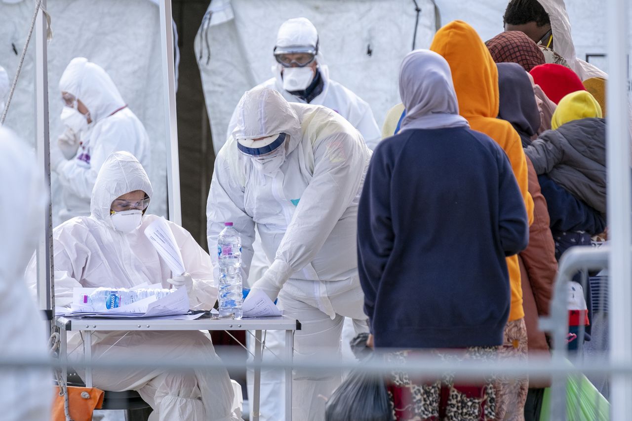 Italian Red Cross agents wearing protective suits and masks register migrants rescued in the Mediterranean as they disembark from the Sea Watch NGO's ship on February 27, in, Messina, Sicily.