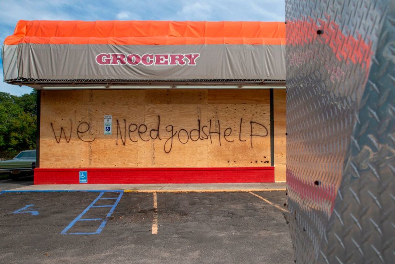 "We Need God's Help" is spray painted on wood boards covering the windows of a grocery store in Myrtle Beach, South Carolina on Sept. 12, 2018. 