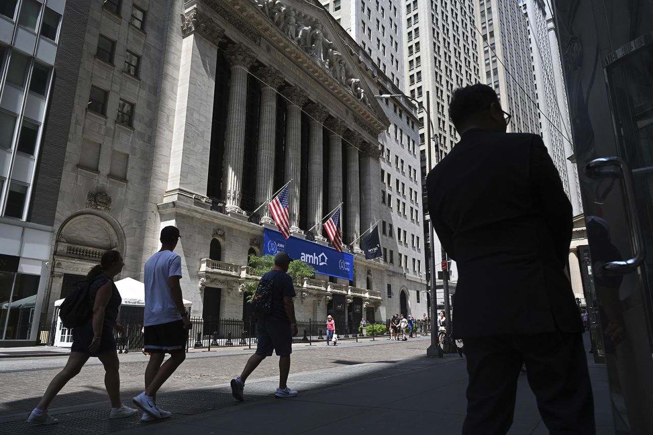 People walk past the New York Stock Exchange on Wall Street on August 1.