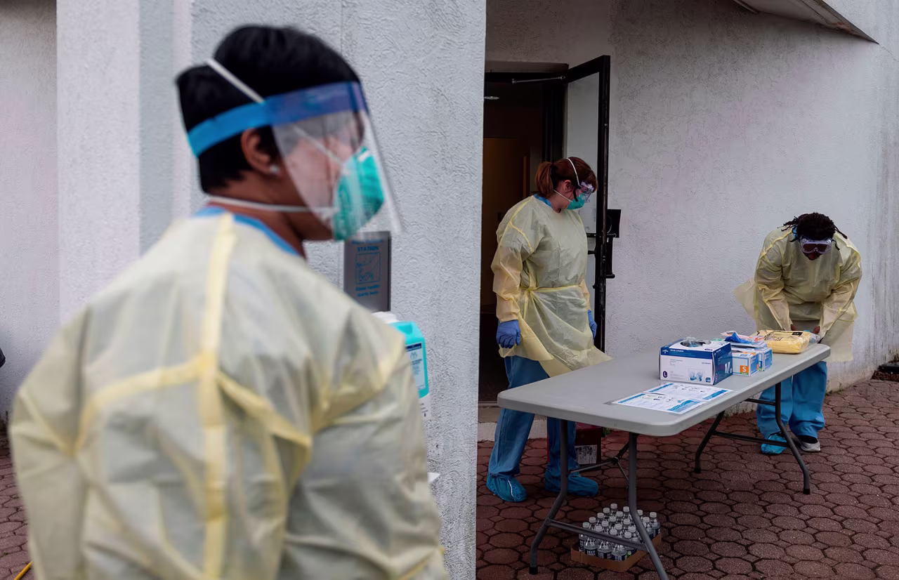 Health care workers put on personal protective equipment at a drive-through testing site in Arlington, Virginia, on March 20, 2020.