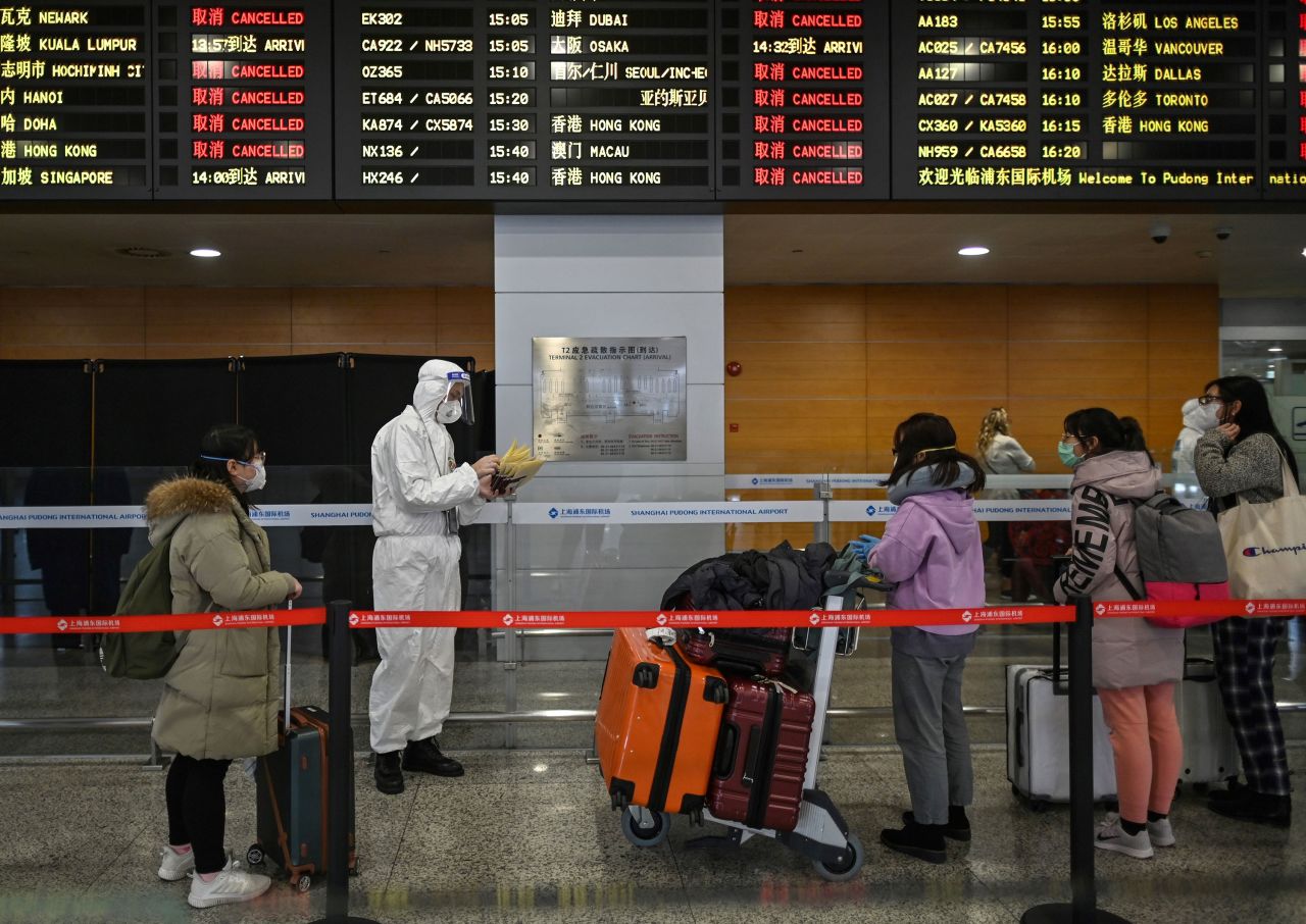 An airport security staff member assists passengers arriving to the Shanghai Pudong International Airport in Shanghai on March 19.