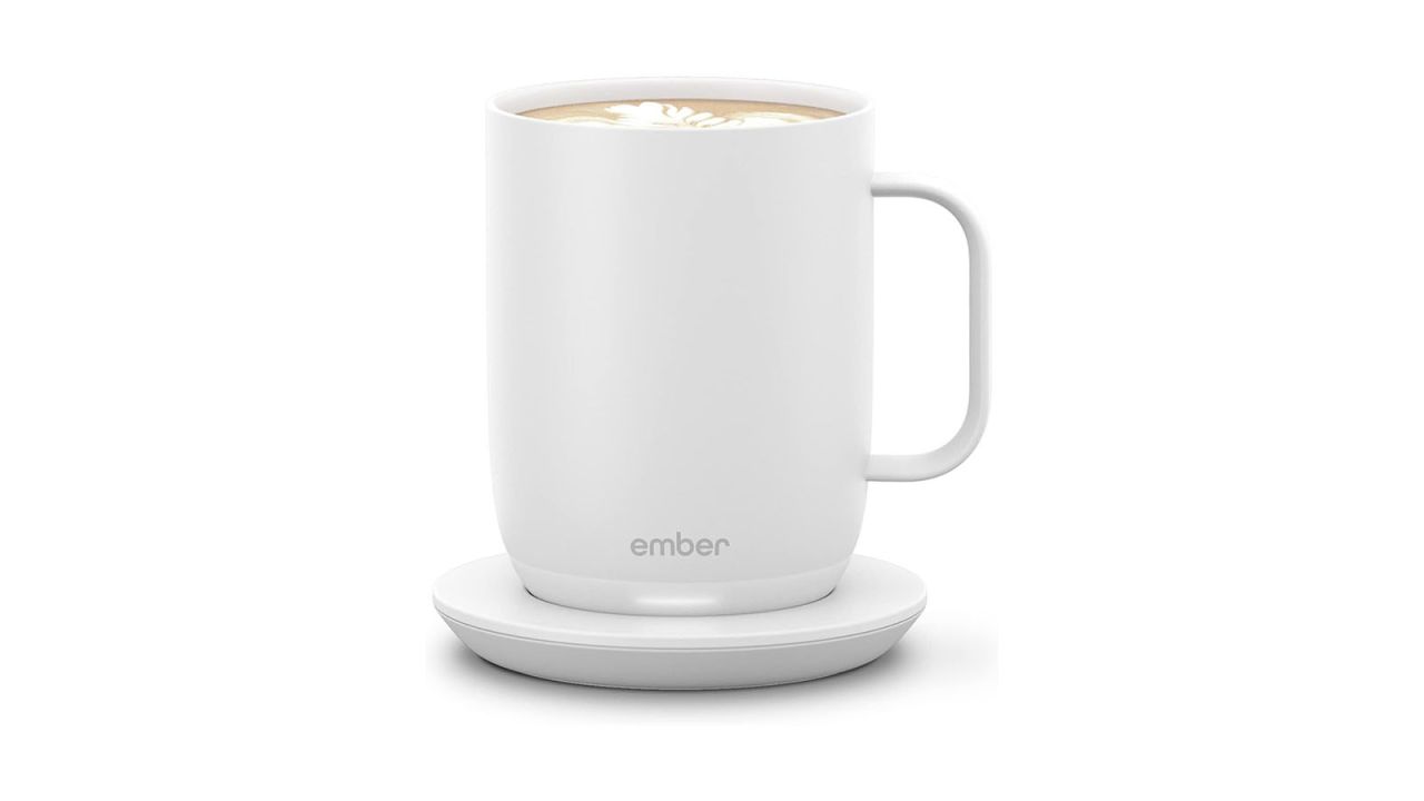 Weißer wiederaufladbarer Becher mit Kaffee darin vor weißem Hintergrund.