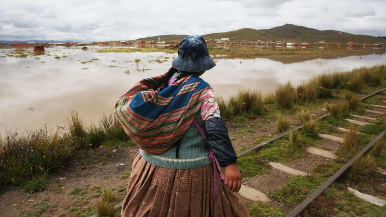 Una mujer camina por el borde de un río tras fuertes lluvias en Viacha, Bolivia.
