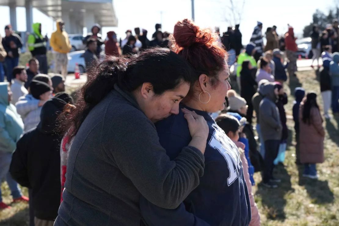 People wait as school buses arrive at a meeting site after the shooting on Wednesday, January 22, 2025.