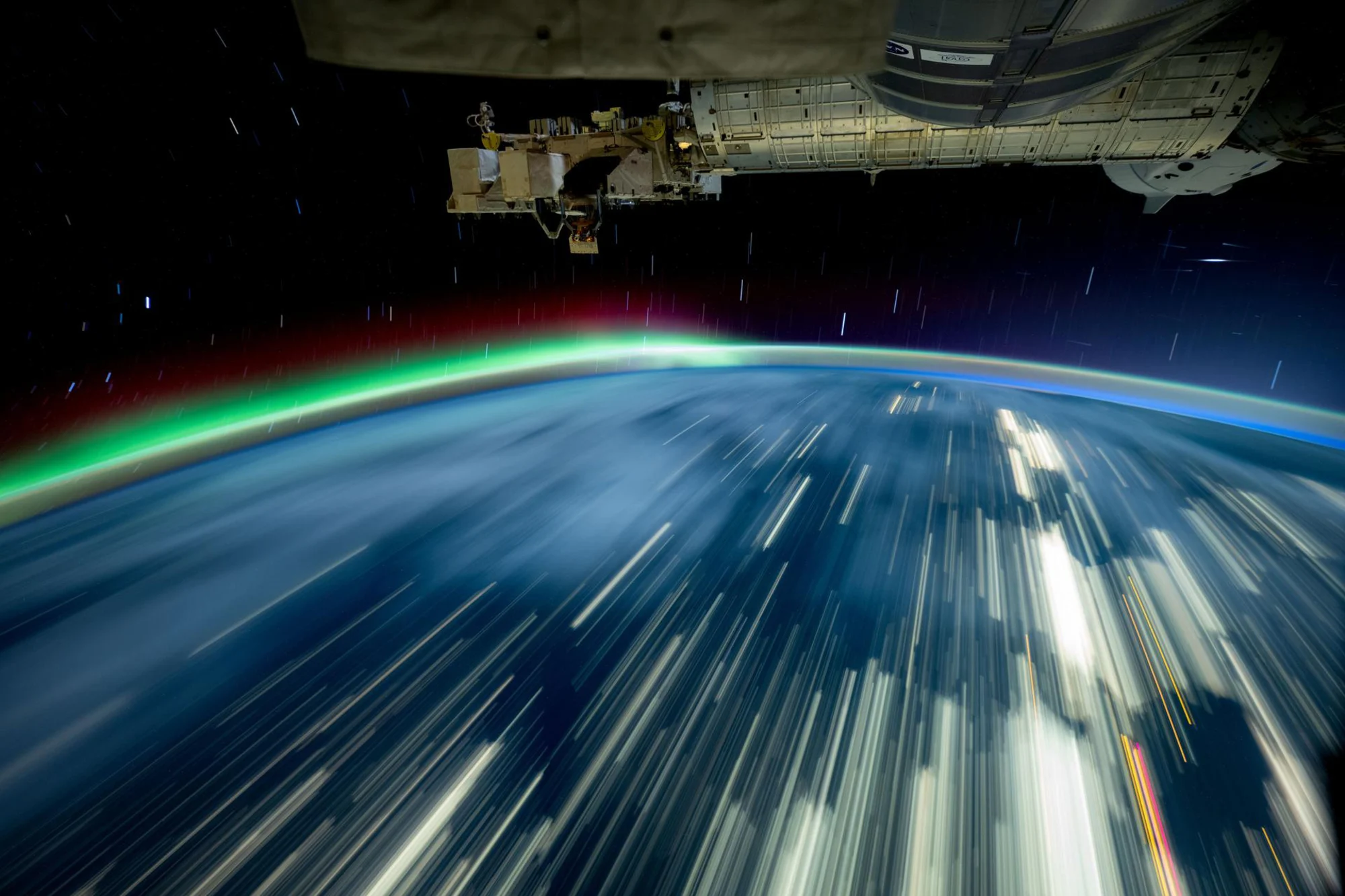 Mientras la Estación Espacial Internacional se elevaba a más de 400 kilómetros sobre el lago Michigan en octubre, Don Pettit de la NASA captura una foto de larga exposición de las luces de la ciudad a través de la Tierra y una aurora roja y verde.