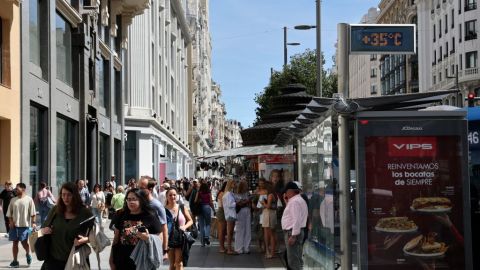 Los visitantes caminan por la calle Gran Vía en el centro de Madrid, mientras un termómetro marca 35 grados centígrados, el 12 de septiembre de 2024.