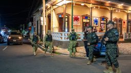 Soldiers patrol a street.