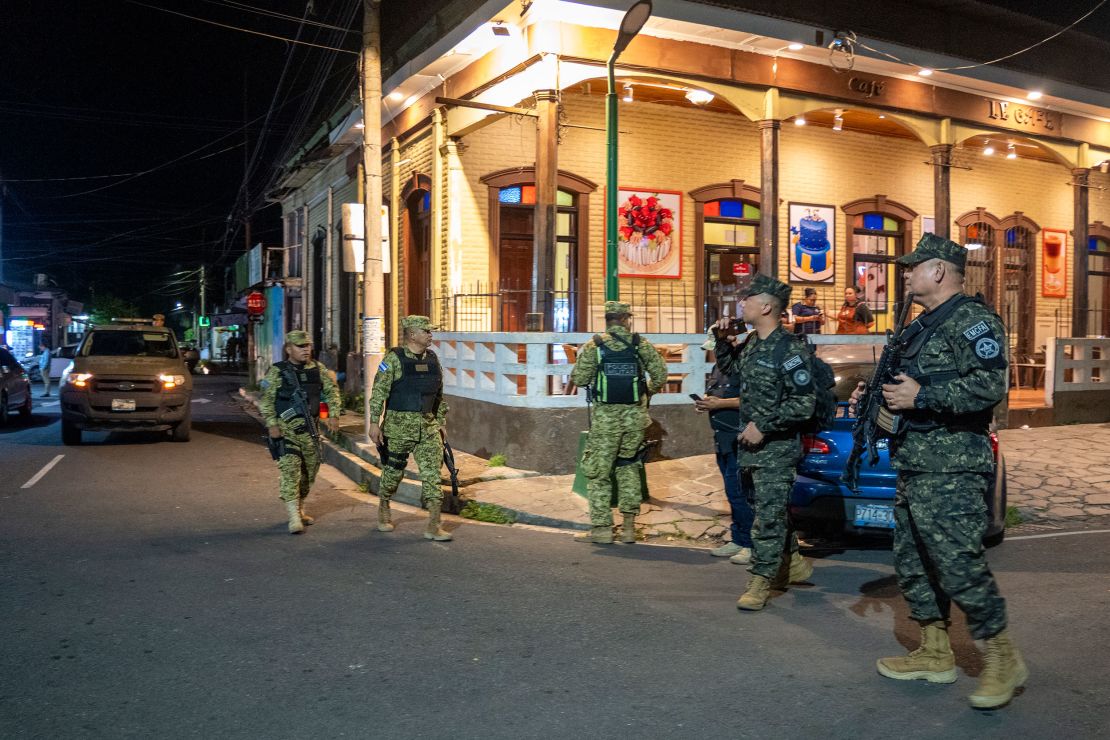 Soldiers patrol a street.