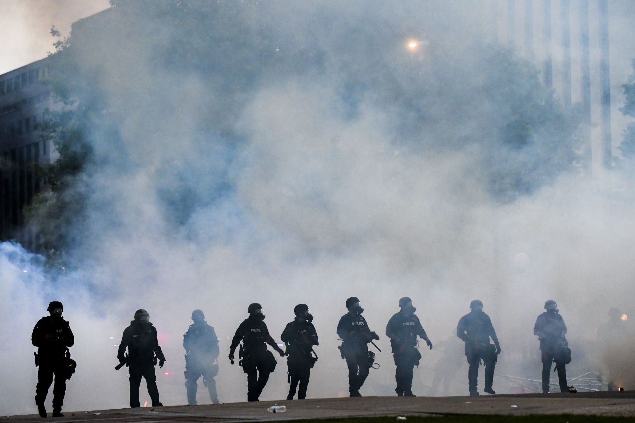 Police officers walk through a cloud of tear gas as they try to disperse protesters in front of the Colorado Capitol  in Denver on May 30.