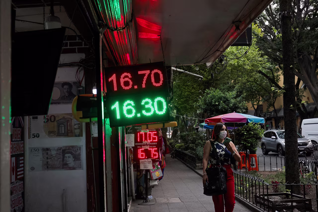 A woman walks past a board showing currency exchange rates of the Mexican peso against the US dollar in Mexico City, on May 28. 