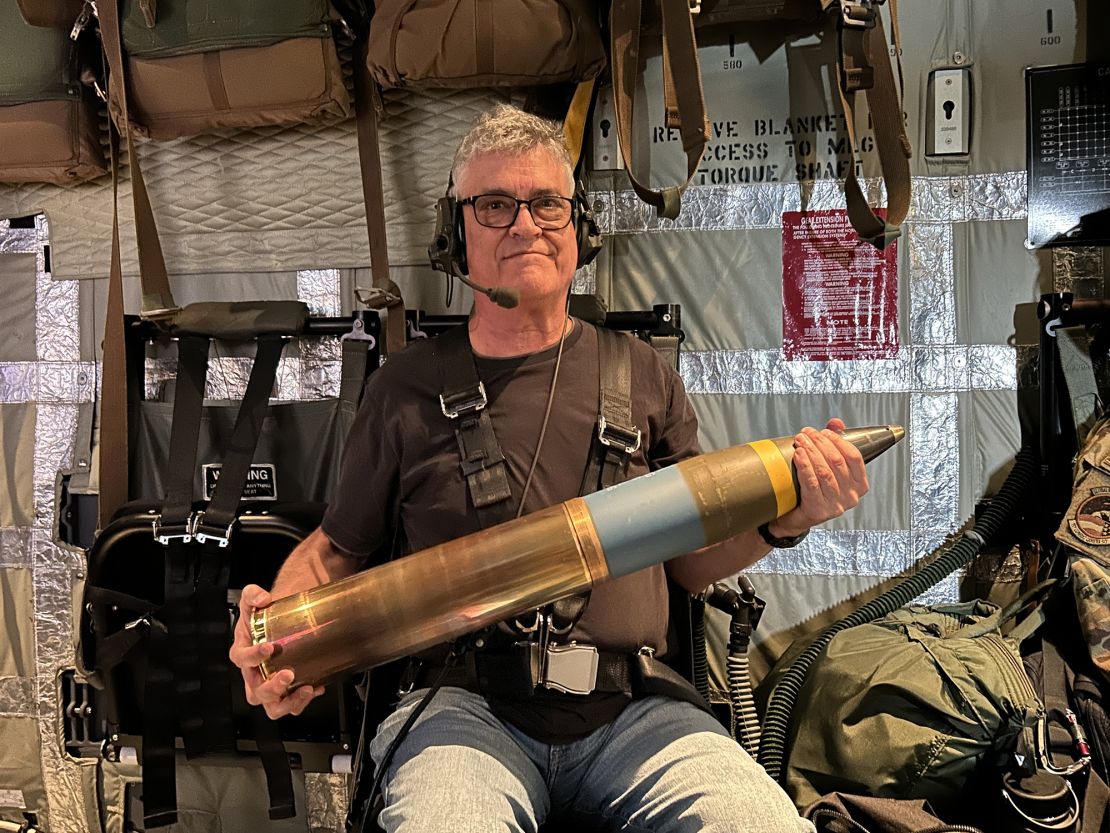 CNN senior global military affairs writer Brad Lendon holds a 105mm howitzer shell aboard a US Air Force AC-130J gunship flying out of Osan Air Base, South Korea, in June 2024