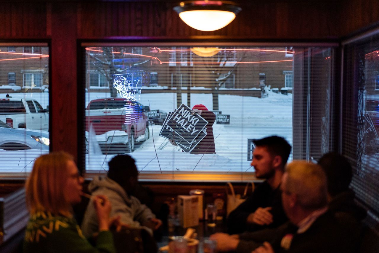 A campaign worker moves signs in front of Drake Diner in Des Moines, Iowa, on Monday. 