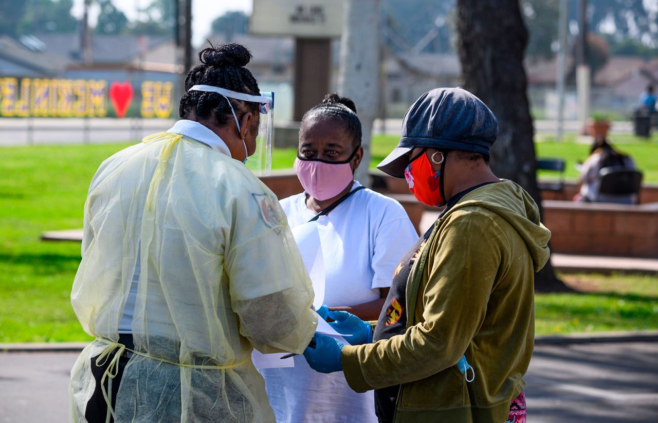 Local residents fill out paperwork at a mobile COVID-19 testing station in a public school parking area in Compton, California, on Tuesday, April 28. St. John's Well Child and Family Center is providing COVID-19 testing sites in African-American and Latino communities which have been neglected in terms of testing as compared to wealthier areas of Los Angeles County.