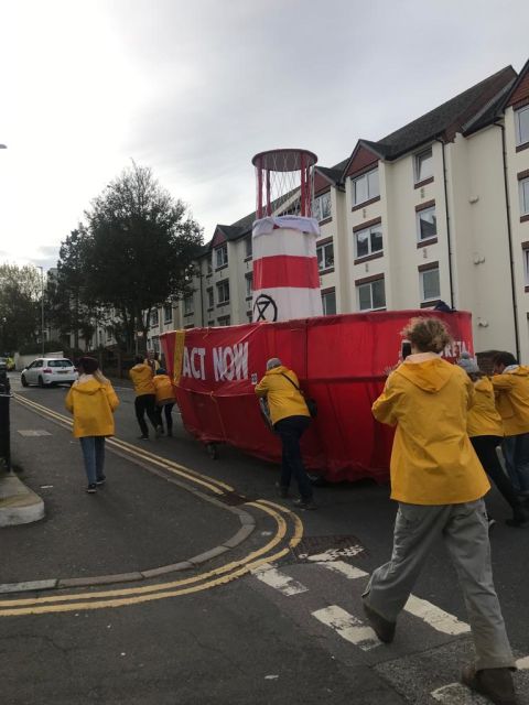 Extinction Rebellion activists push an "Act Now" float through the streets of Brighton on Saturday morning.