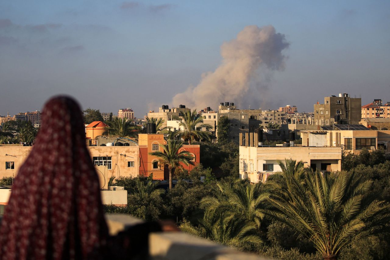 A Palestinian woman watches as smoke billows following an Israeli strike south of Gaza City, in the town of al-Zawaida in the central Gaza Strip, on June 11, 2024.