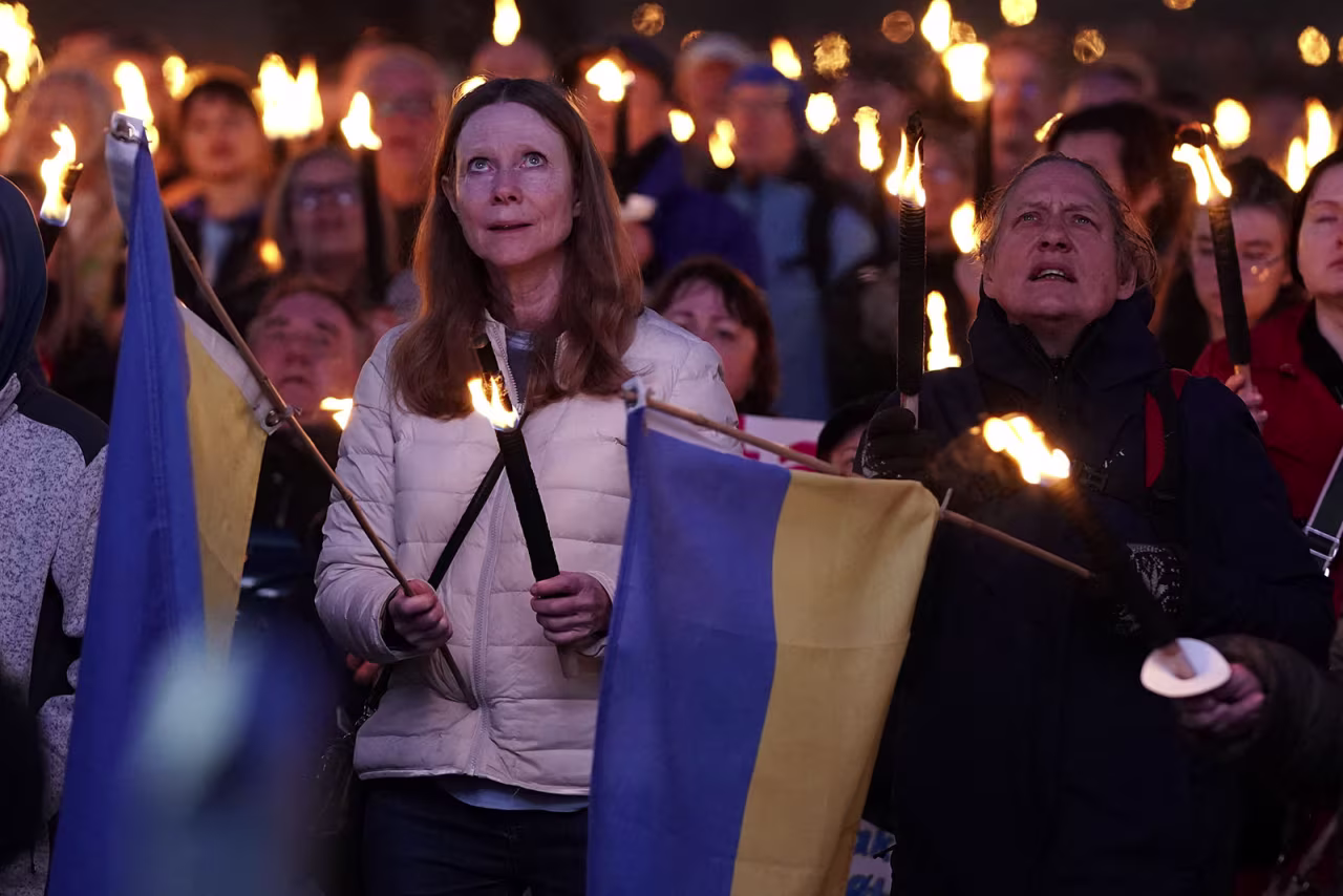 People hold Ukraine flags and torches as Ukrainian President Volodymyr Zelensky addresses people via video at the City Hall Square in Copenhagen on May 4.