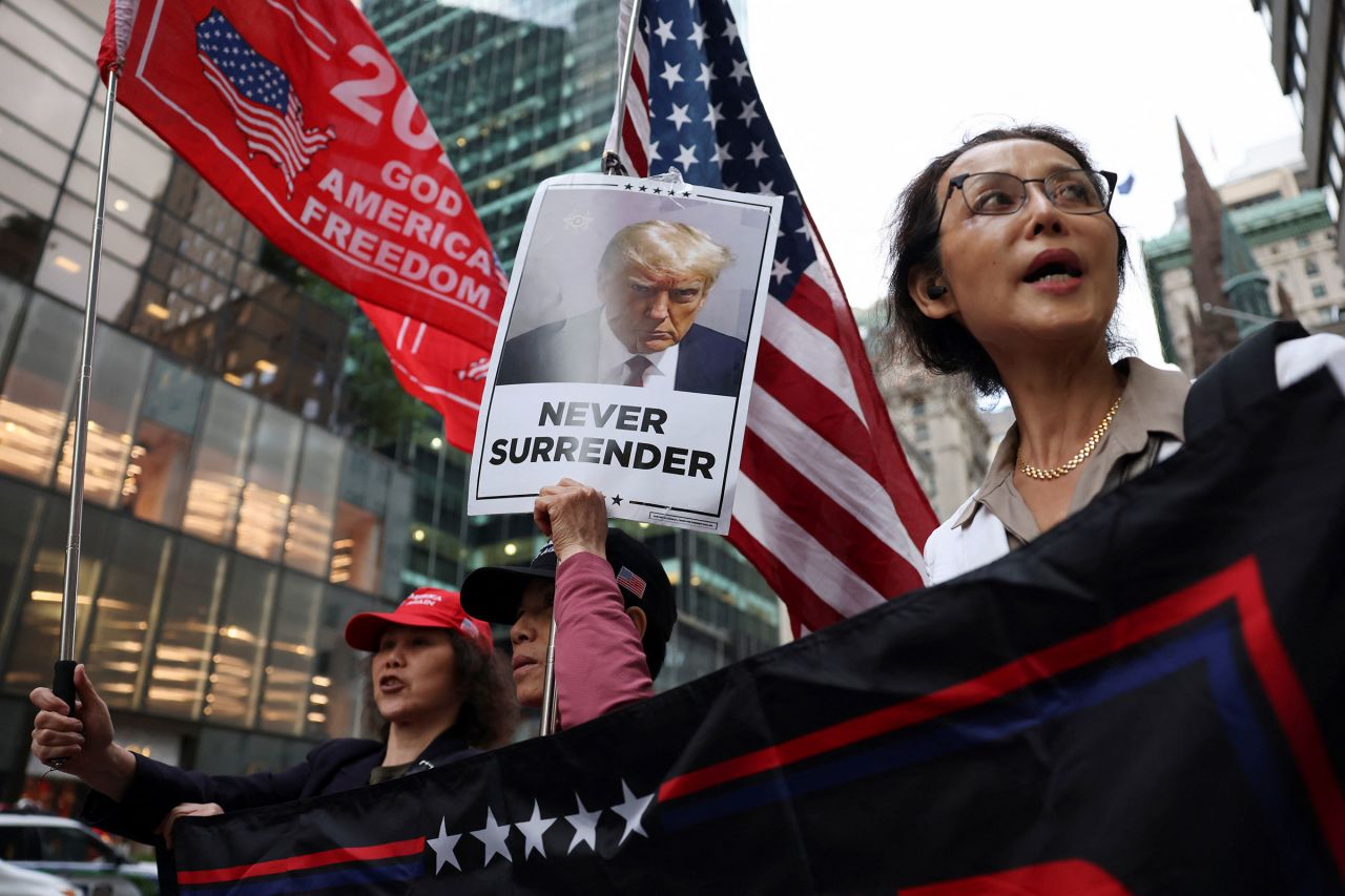 Supporters hold placards and flags following the announcement of the verdict in former President Donald Trump's criminal trial over charges that he falsified business records on May 30.