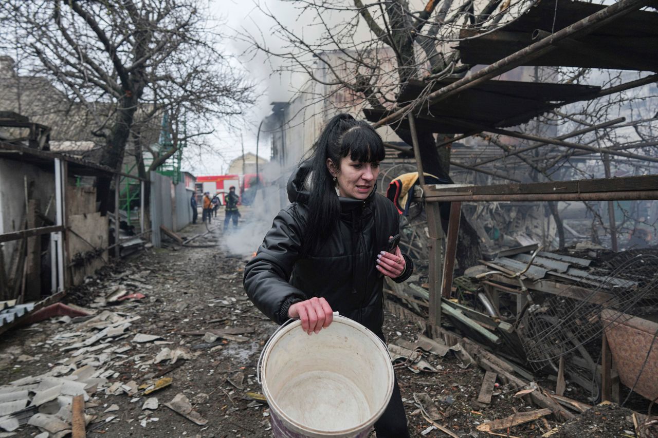 A woman walks past debris in Mariupol, Ukraine, on February 24.