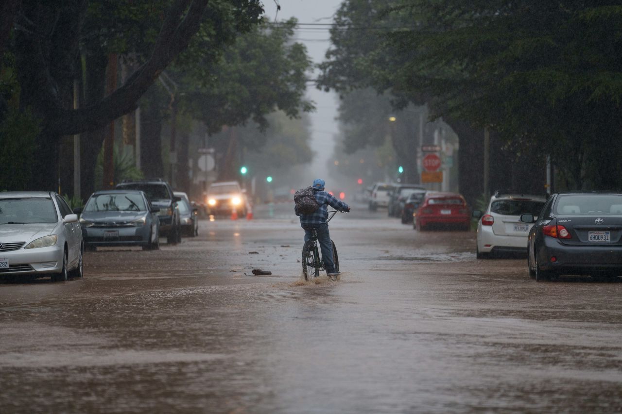 A person rides a bike through floodwater during a storm in Santa Barbara, California, Sunday, February 4. 