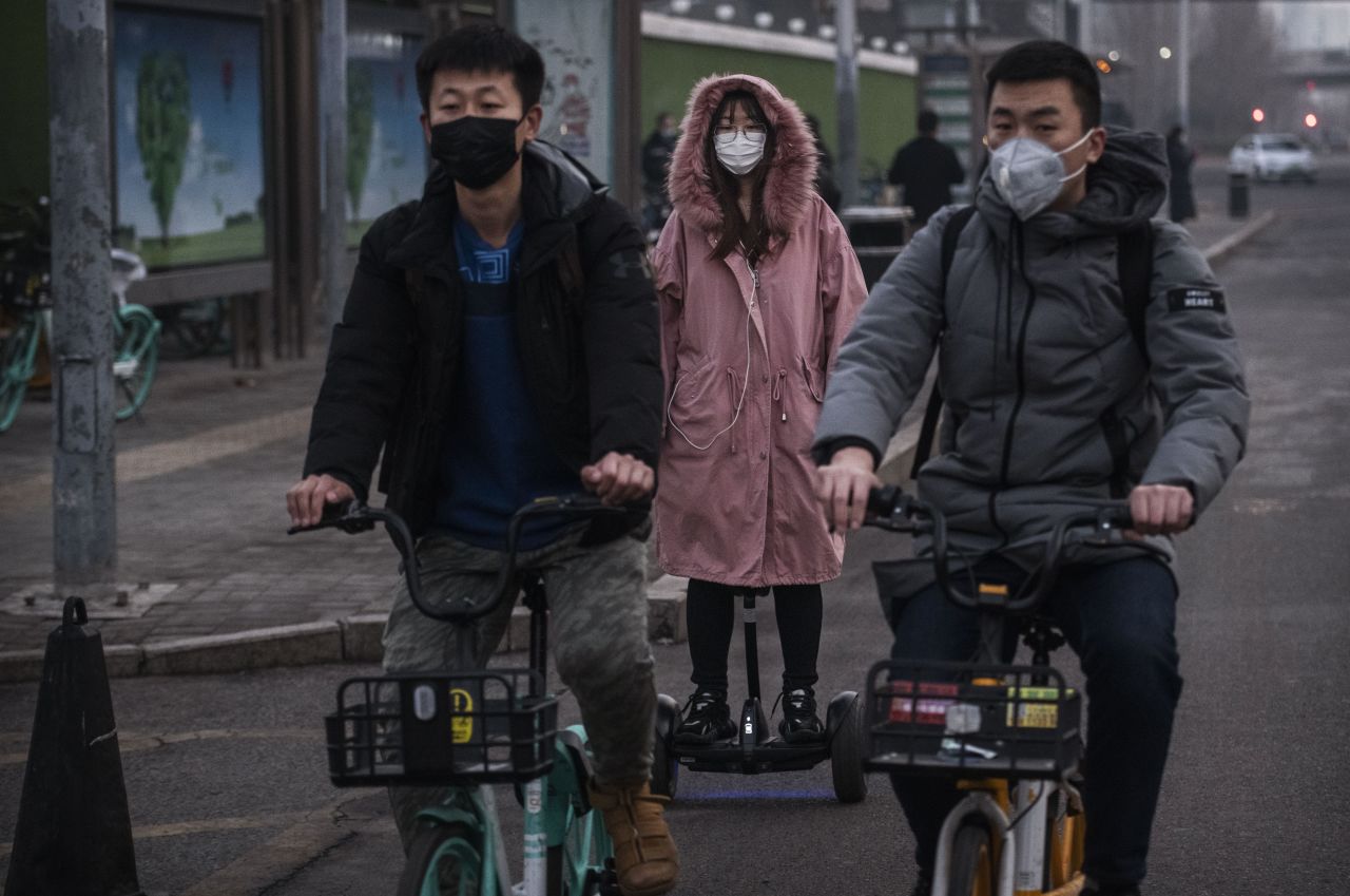 People wear protective masks as they ride in the street during the rush hour on Monday in Beijing.