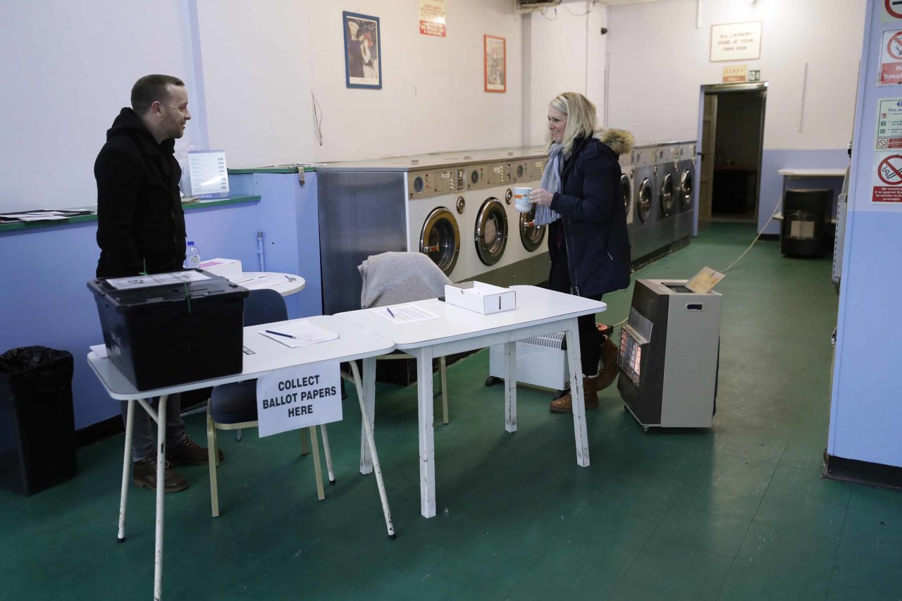 Election officials stand with heaters to keep warm inside a polling station at Ace Laundrette in Oxford, England. Photo: Matt Dunham/AP