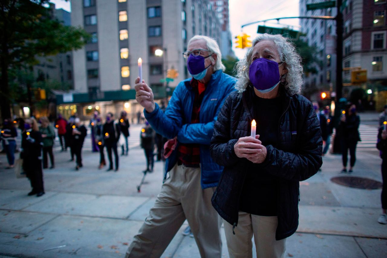 People attend a candlelight vigil a procession in tribute to all of the lives affected by the novel coronavirus outside The Cathedral of St. John the Divine on October 19, in New York City.