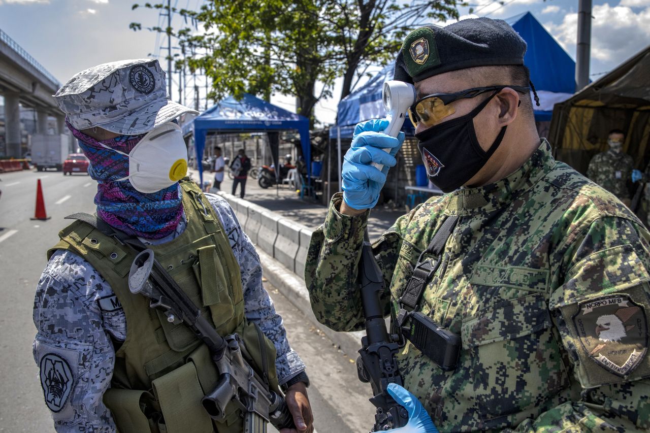 A Filipino policeman checks his own temperature at a quarantine checkpoint on Wednesday in Marikina, Metro Manila.