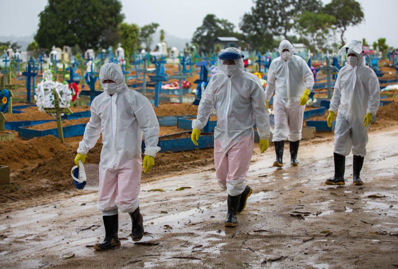 Workers wearing protective suits walk past the graves of COVID-19 victims at the Nossa Senhora Aparecida cemetery, in Manaus, Brazil, on February 25.