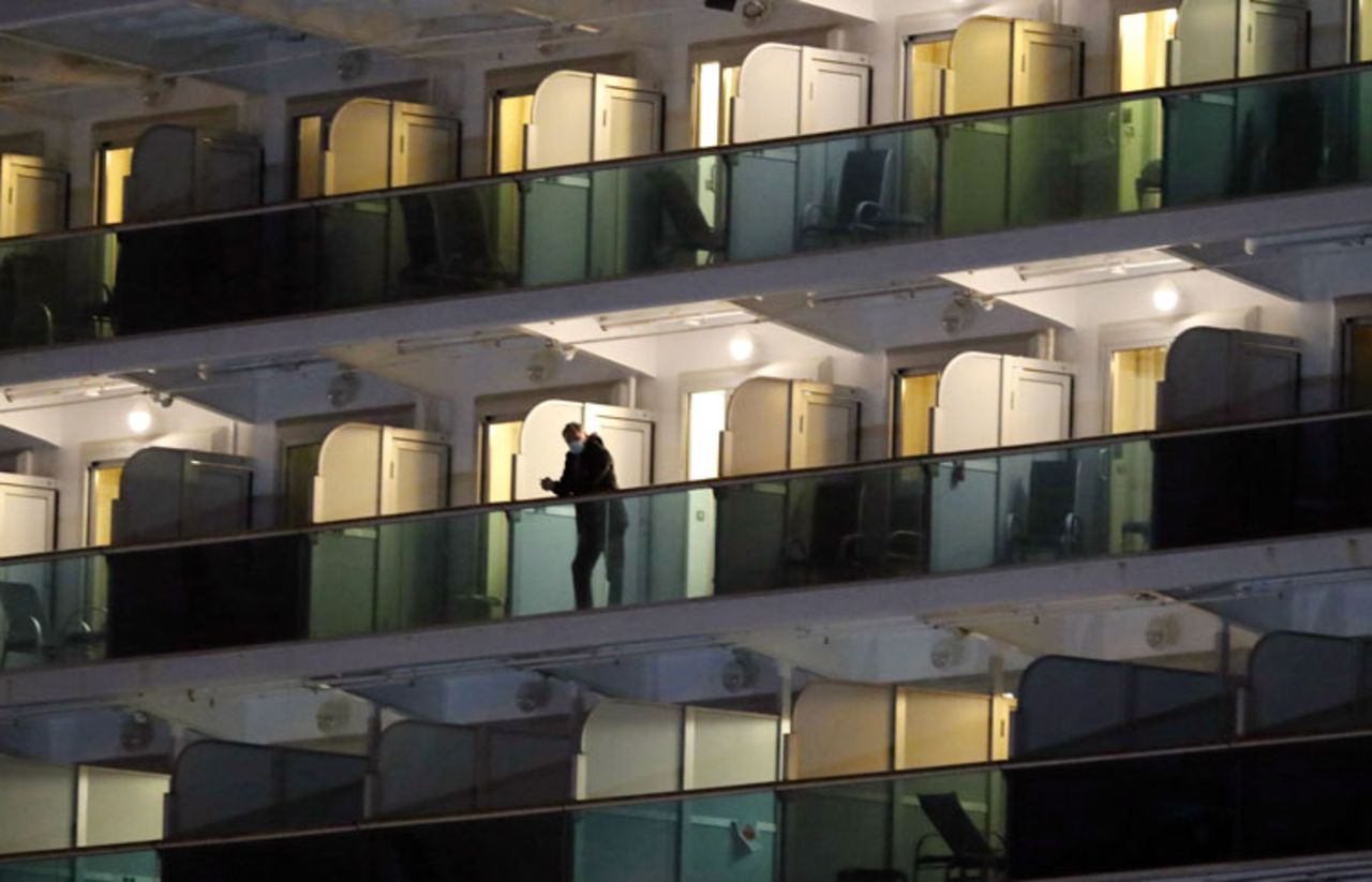 A passenger stands on a cabin balcony of the Diamond Princess cruise ship docked at the Daikoku Pier Cruise Terminal in Yokohama, Japan, on Tuesday, February 18.