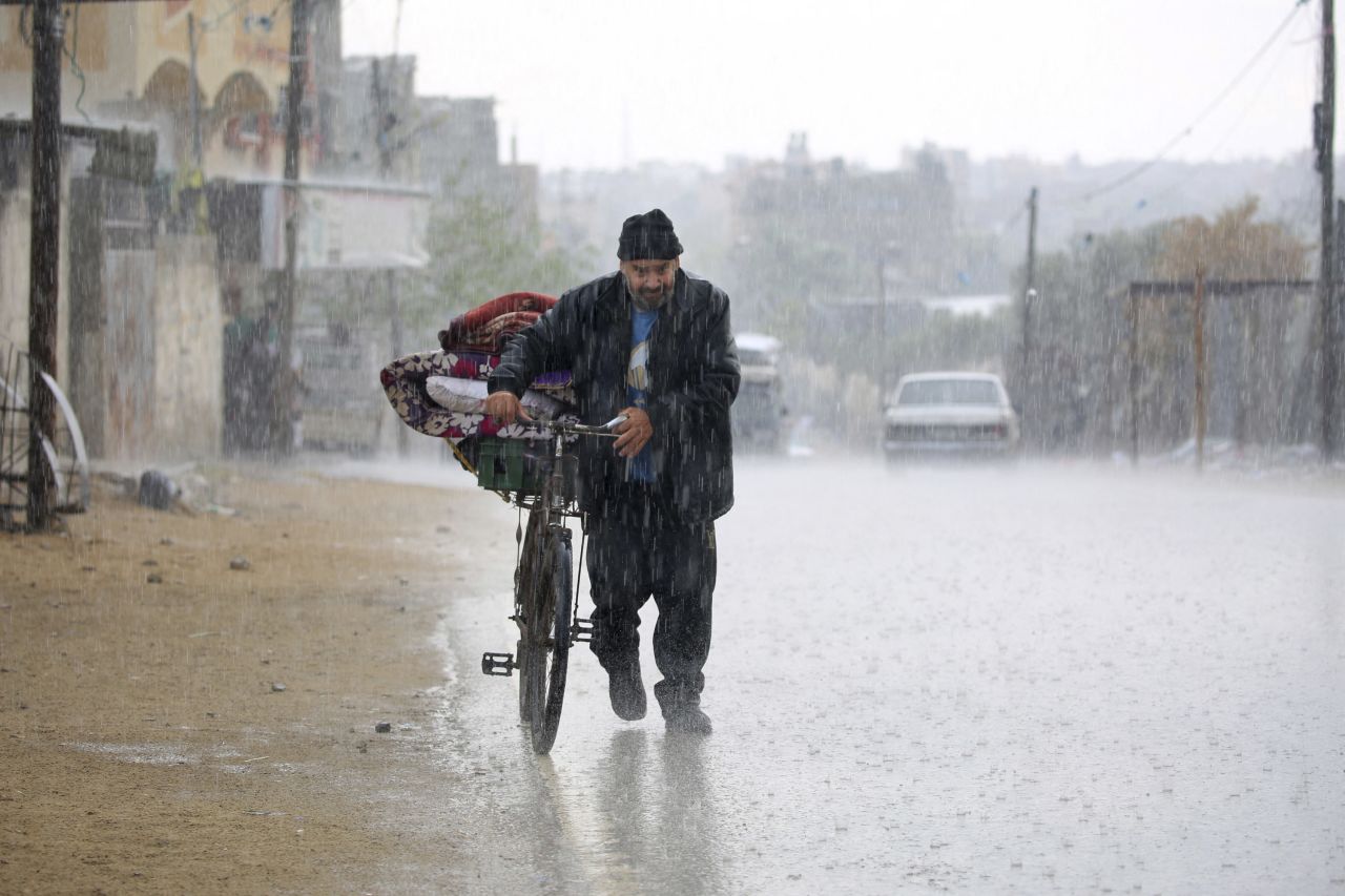 A displaced Palestinian man pushes a bicycle carrying his belongings during a downpour in Rafah on Monday. 