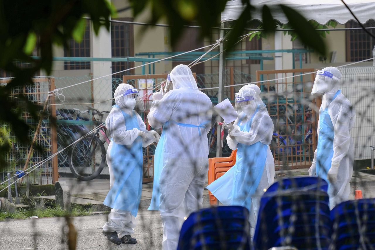 People wearing protective suits are seen behind barbed wire at the Top Glove hostel compound in Klang, Malaysia, on November 23.