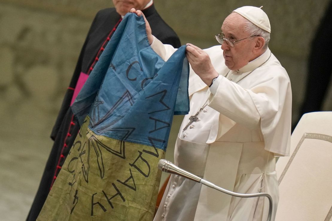 El papa muestra una bandera que le fue traída desde Bucha, Ucrania, durante una de sus audiencias generales en el Vaticano en abril de 2022.