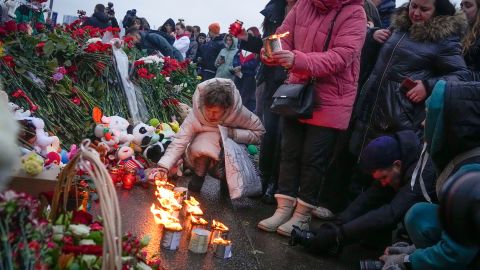 A woman lights candles at a memorial near Crocus City Hall, on the western edge of Moscow, on Saturday. 
