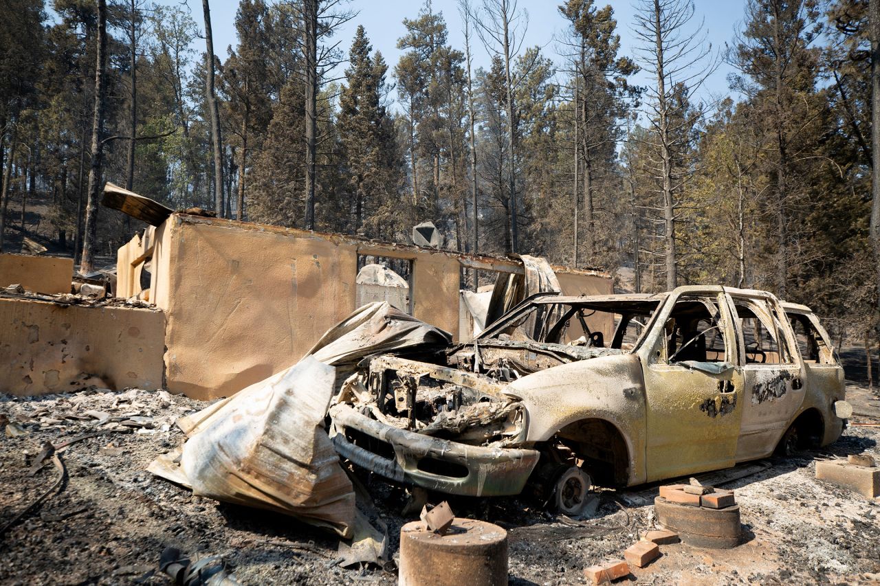 A burned car stands in front of a ruined building as the South Fork Fire burned most of the structures in Cedar Creek after mass evacuations of the village of Ruidoso, New Mexico on June 18.