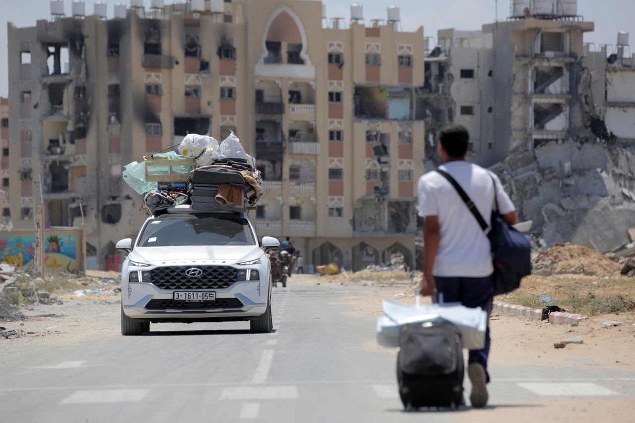 Palestinians who fled Rafah in the southern Gaza Strip carry their belongings from the back of a truck as a man pulls his suitcase upon their arrival to take shelter in Khan Yunis on May 12.