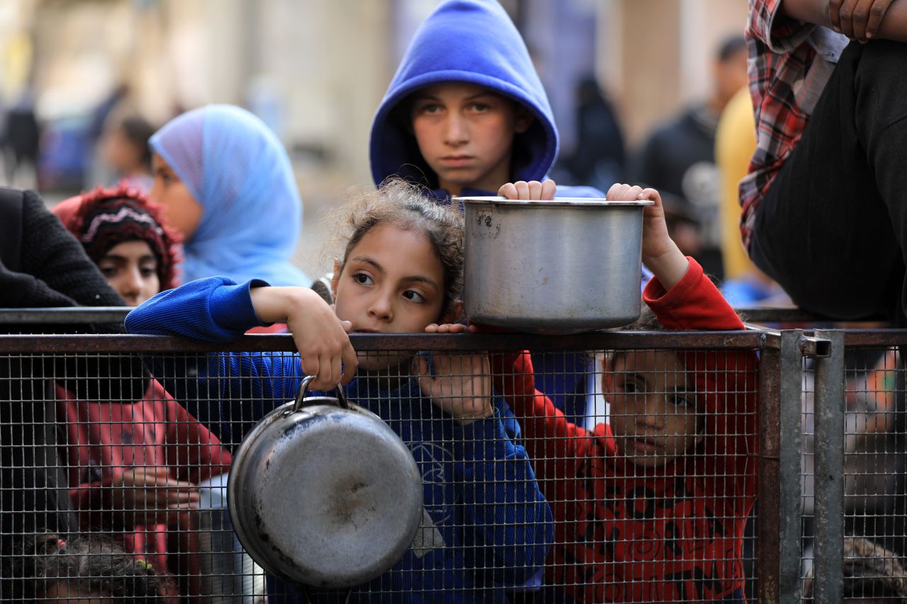 Palestinians hold empty containers to receive food distributed by aid organizations in Rafah, Gaza, on March 30.