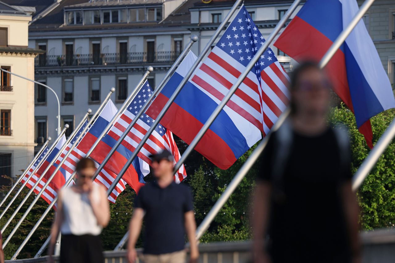 People walk under Russian and American flags on a bridge in the city center prior to a meeting between US President Joe Biden and Russian President Vladimir Putin on June 15, in Geneva, Switzerland. 