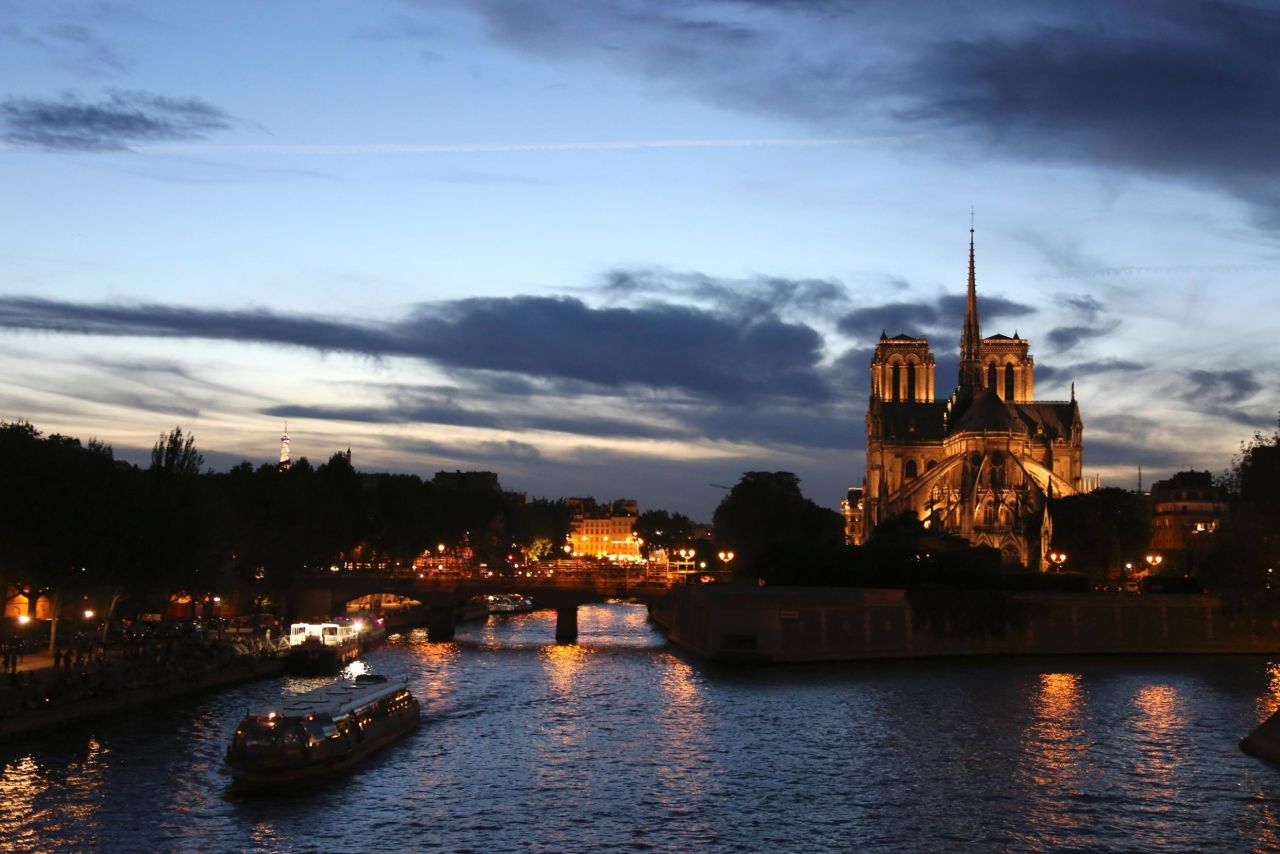 This picture taken in 2016 shows tourist boats cruising on the Seine river alongside the cathedral at sunset.