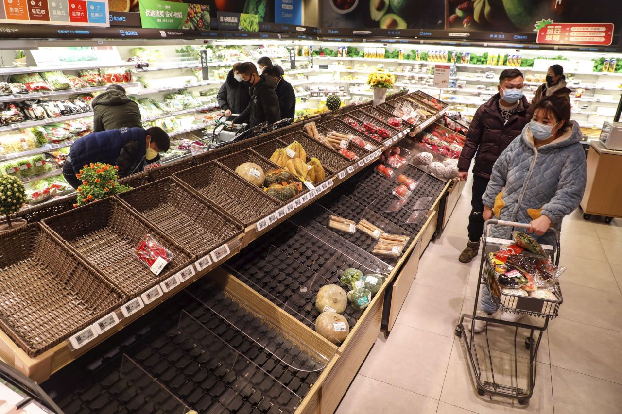 Shoppers wearing face masks look for groceries with many empty shelves at a supermarket in Wuhan?on Saturday.